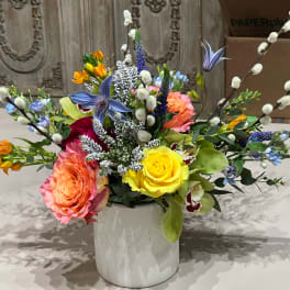 Colorful bouquet of roses and mixed flowers in a white vase