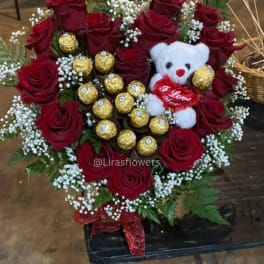 Heart-shaped bouquet of red roses with a teddy bear and gold chocolates