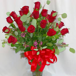Red roses in a clear glass vase with a red ribbon bow