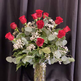 Red roses arranged in a clear glass vase with baby's breath
