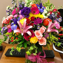 Colorful mixed bouquet in a glass vase with a pink ribbon