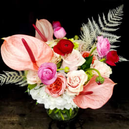 Pink anthuriums and mixed roses in a glass vase