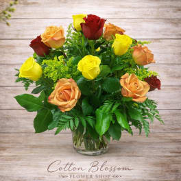 Bouquet of yellow, peach, and red roses in a clear glass vase