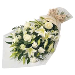 White lilies and roses in a wrapped bouquet with greenery