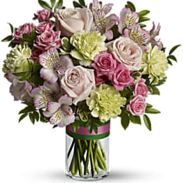 Pink roses, green carnations, and white alstroemeria in a clear glass cylinder vase