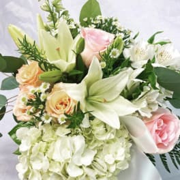 Bouquet of white lilies, pink and peach roses, and white hydrangea
