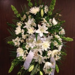 White funeral spray with lilies, chrysanthemums, and ribbon