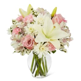Pink and white bouquet with lilies and roses in a clear glass vase