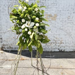 Tall white and green floral standing arrangement on a tripod easel