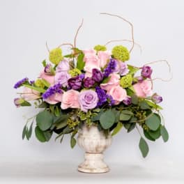 Pink and lavender roses in a white pedestal vase