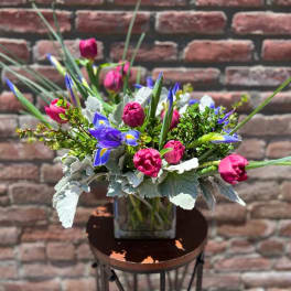 Bouquet of pink and blue flowers in a square glass vase