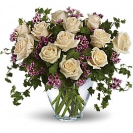 Cream roses with purple filler in a clear glass vase