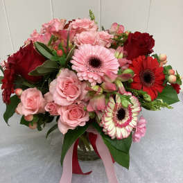 Pink and red mixed bouquet in a glass vase with ribbon