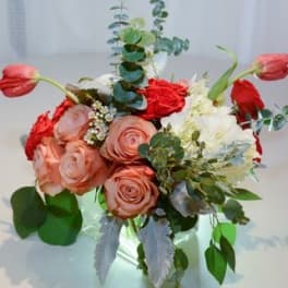 Bouquet of pink and red roses with white flowers in a clear vase