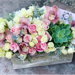 Pink and white roses with orchids and a succulent in a wooden box