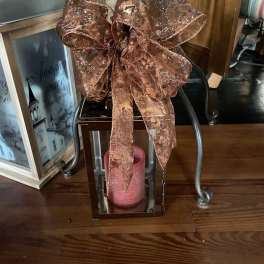 Copper glitter bow on a mirrored lantern with a pink candle inside