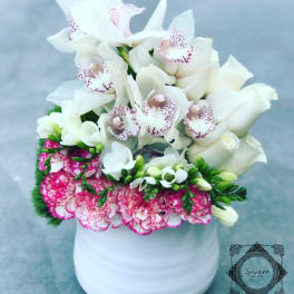 White orchids and pink carnations arranged in a white vase