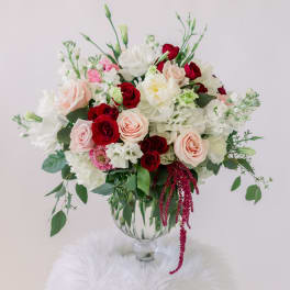 Bouquet of red, blush, and white flowers in a clear glass vase
