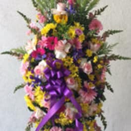 Tall standing floral spray with pink, yellow, and purple flowers and a purple ribbon