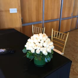 White rose arrangement in a green vase on a black table