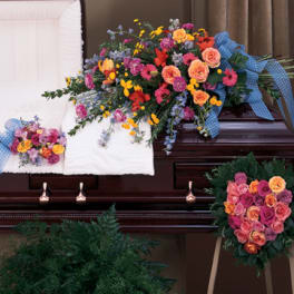 Casket spray and matching floral pieces with pink, orange, and yellow flowers