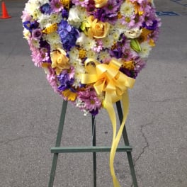 Heart-shaped floral wreath with a yellow ribbon on an easel