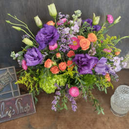 Mixed bouquet of purple, pink, and orange flowers in a basket
