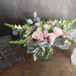Low glass vase of pink carnations, alstroemeria, and white snapdragons with soft gray foliage.