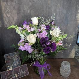 Purple and white bouquet in a glass vase with a ribbon