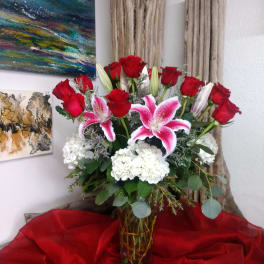 Red roses and pink lilies arranged in a glass vase