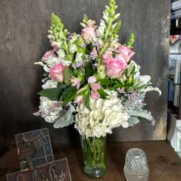 Pink roses and white flowers arranged in a clear glass vase