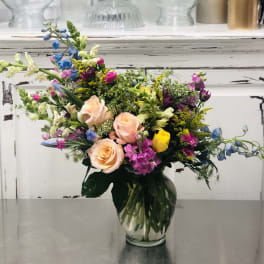 Mixed bouquet of roses and colorful flowers in a clear glass vase