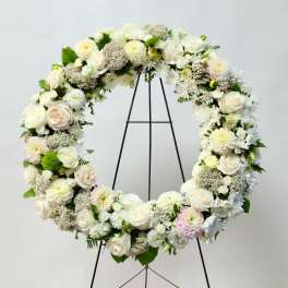 Large white floral wreath on a black stand