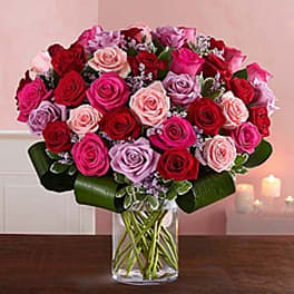 Bouquet of pink, red, and lavender roses in a clear glass vase