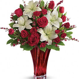 Red roses and white lilies arranged in a red glass vase