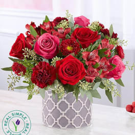 Red and pink rose bouquet in a patterned gray vase