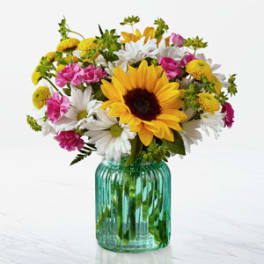 Mixed bouquet with a sunflower and daisies in a teal glass vase