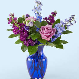 Mixed purple and pink flowers in a blue glass vase