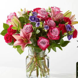 Bouquet of pink and purple roses with lilies in a glass vase