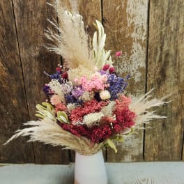Dried flower arrangement in a white and tan vase