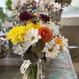 Mixed bouquet in a glass vase with yellow, white, orange, and burgundy blooms