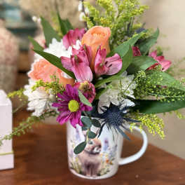 Mixed bouquet in a printed mug vase with pink, peach, and white flowers