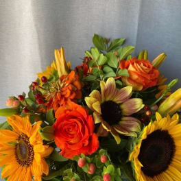 Bouquet of orange roses and sunflowers with green foliage