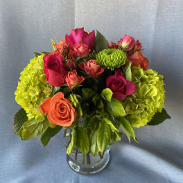 Bouquet of pink and orange roses with green hydrangeas in a glass vase