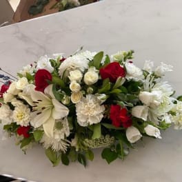Low floral arrangement with red and white blooms on a table