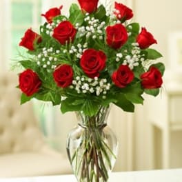 Red roses arranged in a clear glass vase with baby's breath