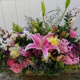 Large mixed floral arrangement with pink lilies and roses in a low container