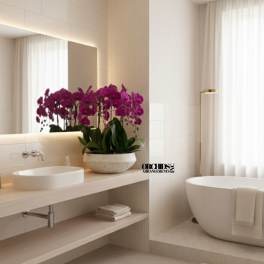 Purple orchid arrangement in a stone bowl on a bathroom counter