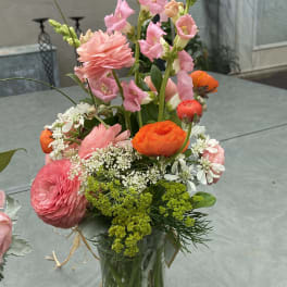 Mixed bouquet in a clear glass vase with pink and orange blooms