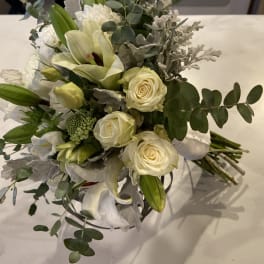White roses and lilies arranged with eucalyptus in a bouquet